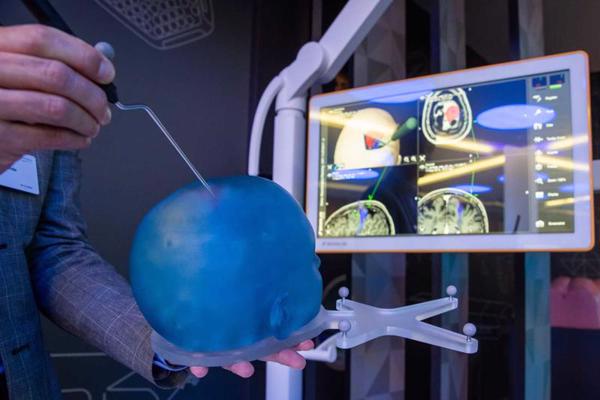 Vācijas uzņēmuma Brainlab AG darbinieks digitālajā samitā demonstrē ķirurģisko iejaukšanos galvaskausa modelī. Medicīnas instruments, kas ir savienots ar datoru, ļauj veikt precīzu medicīnisko iejaukšanos ekrānā redzamajā digitalizētajā galvaskausa anatomijā. Nirnberga, Vācija, 04.12.2018. 