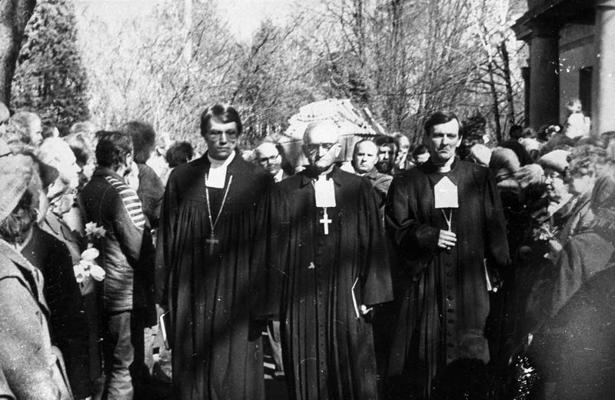 Gunāra Astras bēres Rīgas Otrajos Meža kapos 19.04.1988., šķirstam pa priekšu iet mācītāji (no kreisās) Juris Rubenis, Augusts Ālers un Modris Plāte.