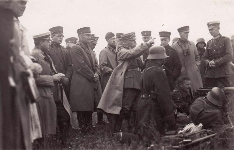 Ģenerālis Jānis Buivids (centrā) un kara akadēmisko kursu klausītāji vēro ložmetējniekus šaušanas mācību laikā. 1927. gads.