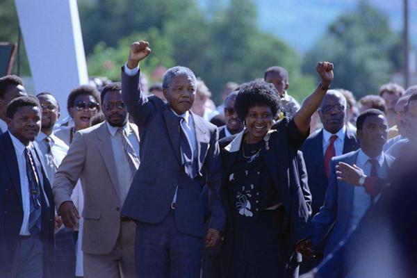 Nelsons Mandela pēc atbrīvošanas no cietuma ar sievu Vinniju Mandelu (Winnie Mandela) dodas garām gavilējošam pūlim. 11.02.1990.