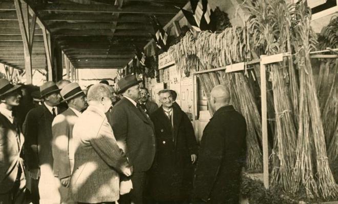 Latvijas Valsts un Ministru prezidents Kārlis Ulmanis aplūko graudkopības paviljona ekspozīciju, viesojoties Latgales Lauksaimniecības izstādē Otro Latvijas Pļaujas svētku laikā Rēzeknē. 14.09.1936.