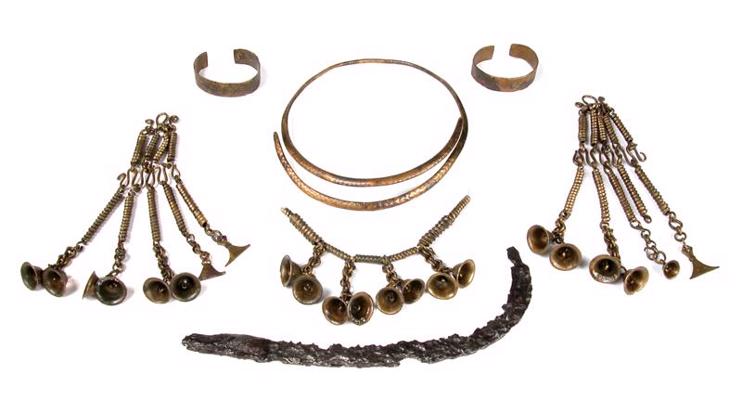 Senlietas no sievietes apbedījuma: bronzas kaklariņķis, aproces, gredzeni, spirāļu un zvaniņu kaklarota un piekari, dzelzs sirpis. Nautrēnu Smiltaine, 7. kaps, 7.–8. gs.