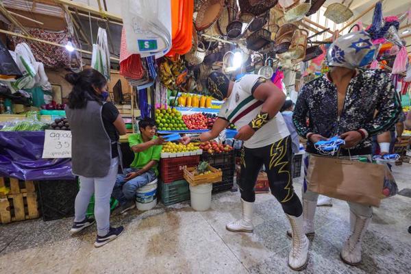 Meksikas brīvās cīņas (lucha libre) cīkstonis kampaņas ietvaros pārdevējam tirgū piedāvā sejas masku, lai veicinātu sejas masku izmantošanu kā profilakses līdzekli pret koronavīrusu. Meksika, 03.09.2020.