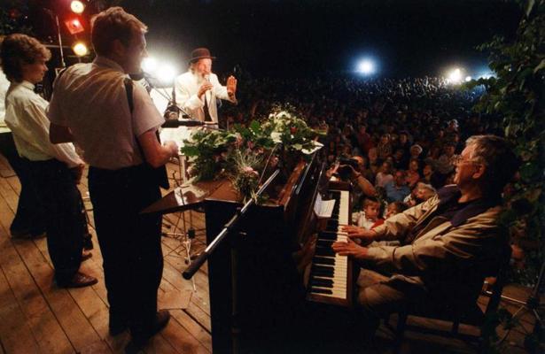 Pie klavierēm Raimonds Pauls, ar mikrofonu aktieris Edgars Liepiņš festivālā "Latvju ziņģe". 1992. gads.