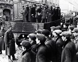 Vērmahta karavīri ebreju vīriešus no Varšavas geto nogādā piespiedu darbā. Polija, 1941. gads.