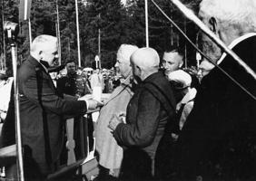 Latvijas Valsts un Ministru prezidents Kārlis Ulmanis (no kreisās) pasniedz Atzinības krusta I pakāpes Goda zīmi Jānim Cinim pirmo Dziesmu svētku 75 gadu Atceres Dziesmu svētkos Dikļu muižas parkā. 16.07.1939.