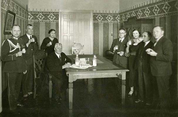 Latvijas Ministru prezidents Kārlis Ulmanis (centrā) kopā ar pavadošām personām azaida laikā dzer pienu. 20. gs. 30. gadi.