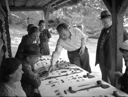 Valdemārs Ģinters (ar cigareti) izrāda arheologam Francim Balodim un vēsturniekam Augustam Tentelim Mežotnes pilskalna arheoloģisko izrakumu senmantas. 1939. gads.