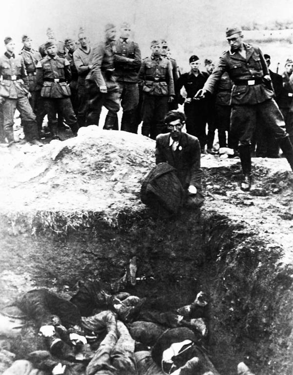 SS operatīvās grupas dalībnieks gatavojas nošaut Polijas ebreju, kurš nometies ceļos pie masu kapa. 1942. gads.