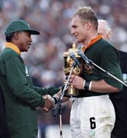 Dienvidāfrikas Republikas prezidents Nelsons Mandela (Nelson Mandela) pasniedz pasaules čempionu kausu Dienvidāfrikas Republikas izlases kapteinim Fransuā Pienāram (François Pienaar). Dienvidāfrika, 1995. gads.
