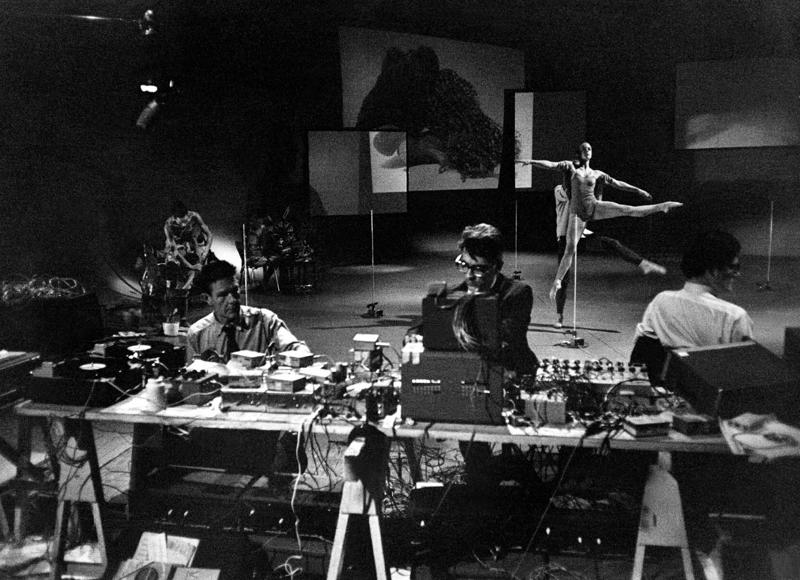 No kreisās: komponisti Džons Keidžs, Deivids Tjūdors (David Tudor) un Gordons Mumma (Gordon Mumma), fonā Barbara Loida (Barbara Lloyd) amerikāņu horeogrāfa Mērsa Kaningema (Merce Cunningham) deju kompānijas baletā "Piecas variācijas" (Variations five). Hamburga, Vācija, 1966. gads.