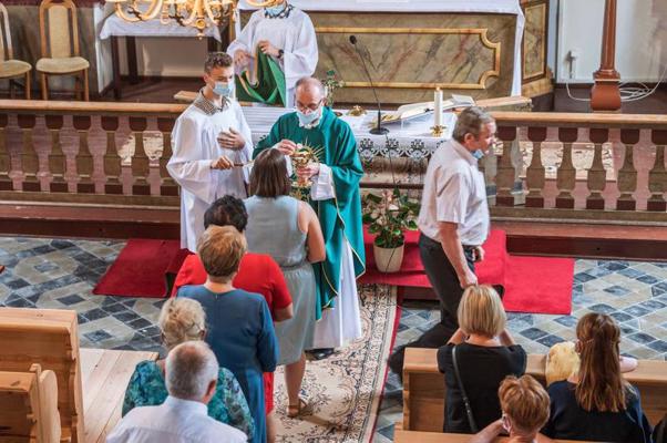 Priesteris dievkalpojuma laikā draudzes locekļiem dod iesvētīto maizi. Polija, 04.07.2021.