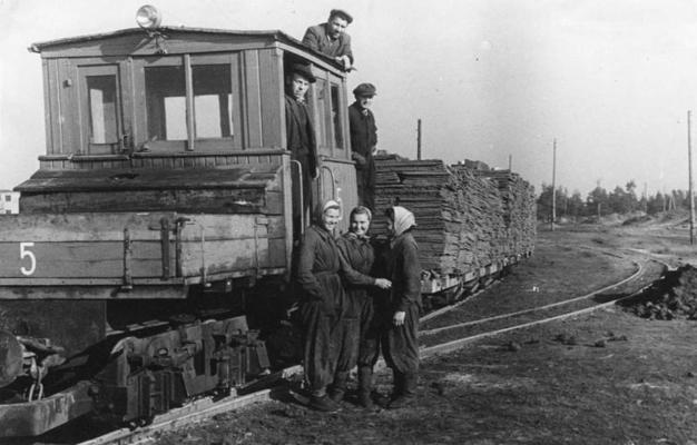 Baložu kūdras fabrikas strādnieki ar lokomotīvi transportē kokšķiedras plāksnes. 20. gs. 60. gadi.