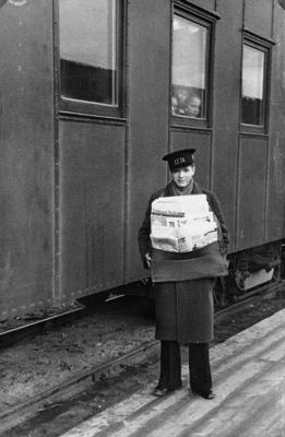Latvijas Telegrāfa aģentūras LETA avīžu zēns tirgo avīzes dzelzceļa stacijā. Rīga, 1934. gads.