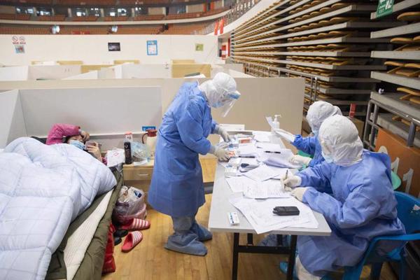 Pacients un medicīniskie darbinieki speciāli Covid-19 pandēmijai radītajā slimnīcā. Uhaņa, Ķīna, 14.02.2020.