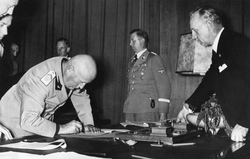 Benito Musolīni paraksta Minhenes līgumu, no viņa pa labi: Vācijas ārlietu ministrs Joahims fon Ribentrops. Minhene, 09.30.1938.