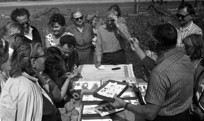 Arheologu ekskursantu grupa aplūko Ķivutkalna kapulauka izpētē iegūtās senlietas. Dole, Rīgas rajons, 04.08.1966.