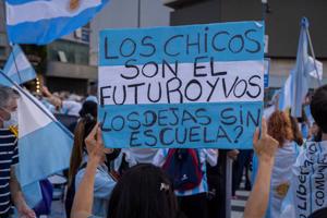 Plakāts pret skolu slēgšanu protesta laikā Buenosairesā, Argentīnā. Tekstā redzams voseo lietošanas piemērs (vos dejás). 17.04.2021.