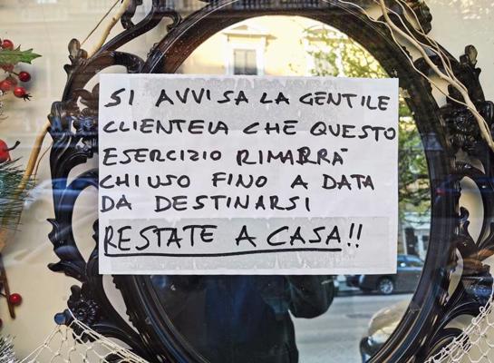 Uzraksts itāļu valodā veikala skatlogā aicina klientus palikt mājās, jo nenoteiktu laiku veikals būs slēgts. Roma, Itālija, 04.04.2020.