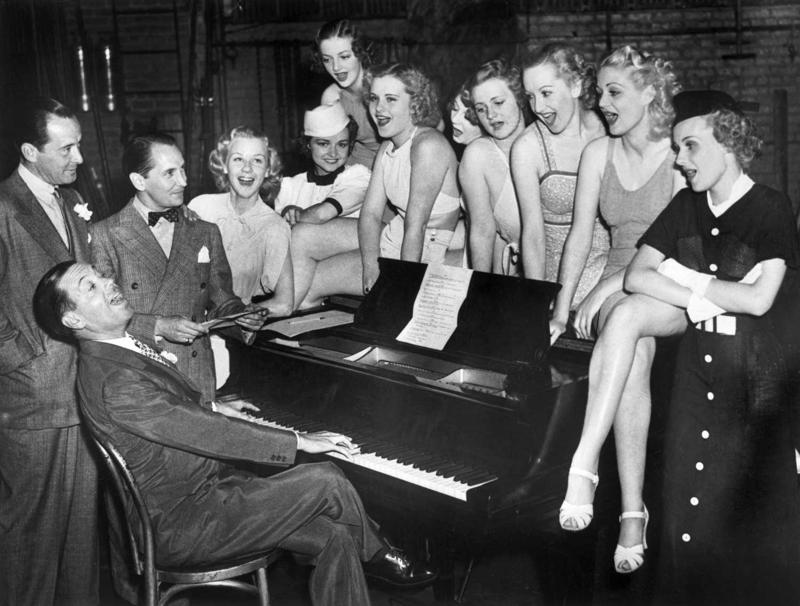 Kouls Porters (sēž pie klavierēm) mūzikla "Pagaidīsim mazulīti" (Wait for Baby) mēģinājumā ar producentu Vintonu Frīdliju (Vinton Freedley, no kreisās), horeogrāfu Džordžu Heilu (George Hale) un potenciālajām mūzikla dalībniecēm. Ņujorka, 07.07.1936.