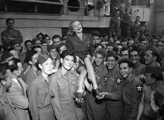 Marlēne Dītriha sveic amerikāņu kājinieku divīzijas karavīrus pēc karadienesta. Ņujorka, ASV, ap 1945. gadu.