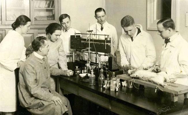 LU Medicīnas fakultātes Farmakoloģijas institūta vadītājs profesors Cēzars Amslers (sēž priekšplānā) ar līdzstrādniekiem laboratorijā. Ap 1930. gadu.