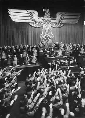 Reihstāga locekļi salutē himnas laikā pēc tam, kad Ādolfs Hitlers (centrā pa kreisi) nosodījis 1919. gada Versaļas miera līguma “Vainas klauzulu”. Berlīne, 30.01.1937.