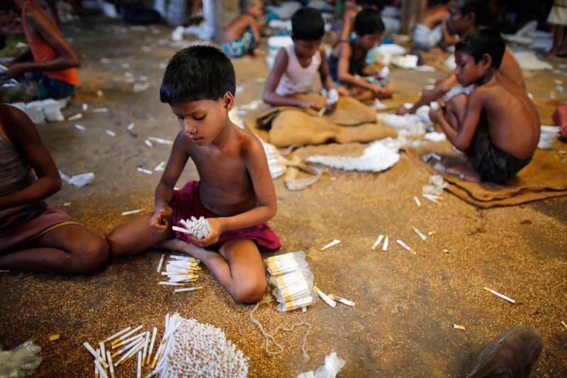 Bērni pilda cigaretes ar vietējo tabaku nelielā rūpnīcā. 2011. gadā publicētā pētījumā par lēto cigarešu ražošanu Bangladešā uzsvērts, ka bērni strādā slikti vēdinātā telpā un ir pakļauti tabakas dūmiem, kas var radīt dažādas veselības problēmas. Bangladeša, 2013. gads.