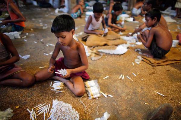 Bērni pilda cigaretes ar vietējo tabaku nelielā rūpnīcā. 2011. gadā publicētā pētījumā par lēto cigarešu ražošanu Bangladešā uzsvērts, ka bērni strādā slikti vēdinātā telpā un ir pakļauti tabakas dūmiem, kas var radīt dažādas veselības problēmas. Bangladeša, 2013. gads.